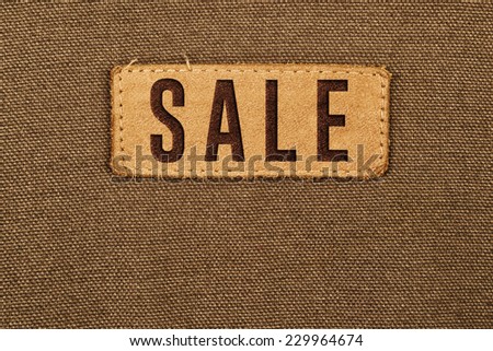 Sale Leather Label Tag on cotton fabric texture background.