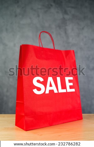 Clearance Sale Red Paper Shopping Bag on Wooden Retail Store Table.