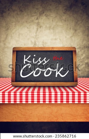 Kiss The CookTitle in white chalk on Restaurant Blackboard. Food and Nutrition background.