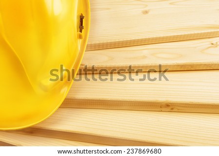 Yellow hardhat on pine wood planks as copy space for carpentry job concept