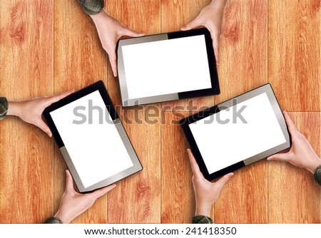 Top View of Hands Holding Three Digital Tablet Computers with Blank White Screens as Copy Space over wooden background