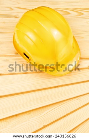 Yellow hardhat on pine wood planks as copy space for carpentry job concept, top view