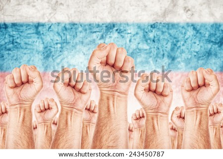 Russia Labor movement, workers union strike concept with male fists raised in the air fighting for their rights, Russian national flag in out of focus background.