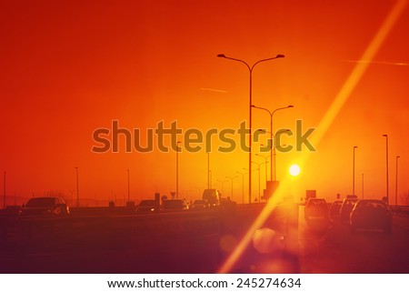 City Traffic in Sunset, Cars driving on Roadway, Toned image with Sun Flare