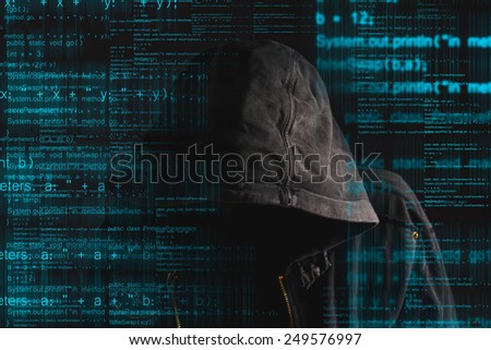 Faceless hooded anonymous computer hacker with programming code from monitor, deep web concept
