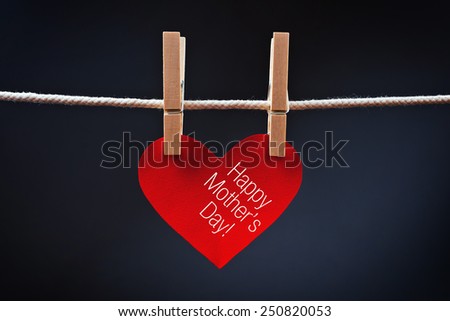 Happy Mother\'s Day printed on red heart attached to rope with clothes pins.