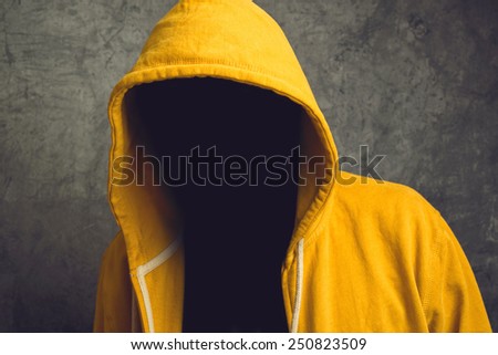 Faceless unknown and unrecognizable person without identity wearing yellow hooded jacket.