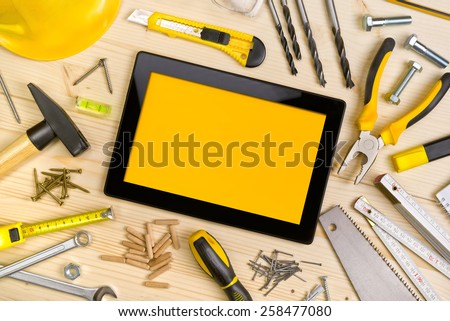 Top View of Digital Tablet and Assorted Woodwork and Carpentry Tools on Pinewood Workshop Table