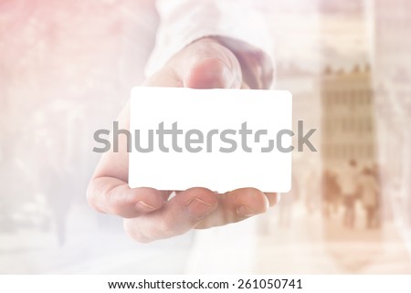 Businessman holding blank visiting card with rounded corners, double exposure image with people on the street, selective focus with shallow depth of field