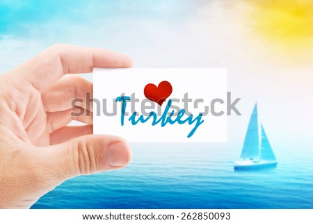 Summer Vacation on Turkish Beach, Person Holding Visiting Card for Summertime Holiday Message Love Turkey and Sailboat at Sea in Background.