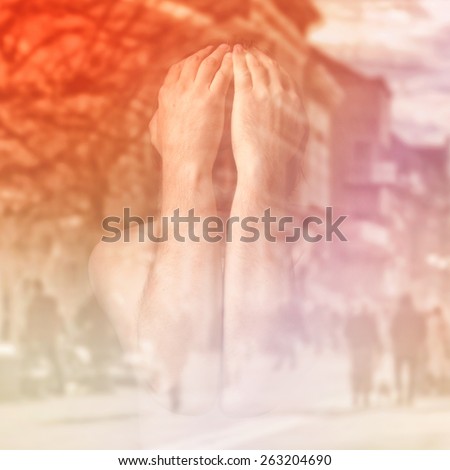 Sad man is covering his face with hands and crying in despair, double exposure image with unrecognizable people walking on street.
