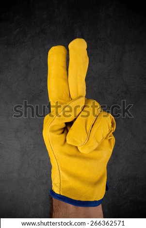 Male Hand in Yellow Leather Construction Engineer or Builder Working protective Gloves Making Two Fingers Gesture.