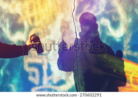 Shadow of Unrecognizable Adult Male Graffiti Artist Spraying the Wall with Canned PAint, Urban Outdoors Street Art Concept, Toned Image with Selective Focus