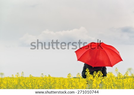 Person with Red Umbrella Standing in Oilseed Rapeseed Agricultural Field as Crop Protection Agrotech Concept, Selective Focus with Shallow Depth of Field