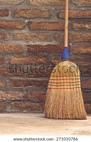 Household Used Broom For Floor Dust Cleaning Leaning on Brick Wall, Vertical