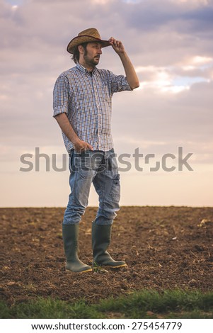 Portrait of Adult Male Farmer Standing on Fertile Agricultural Farm Land Soil,Looking into Distance.