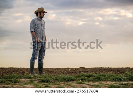 Portrait of Adult Male Farmer Standing on Fertile Agricultural Farm Land Soil Looking into Distance Portrait of Adult Male Farmer Standing on Fertile Agricultural Farm Land Soil Looking into Distance