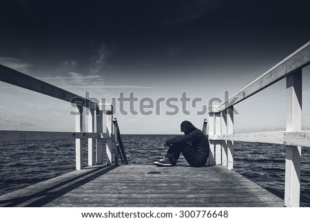 Alone Young Man Sitting at the Edge of Wooden Pier - Hopelessness, Solitude, Alienation Concept, Black and White
