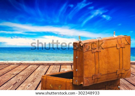 Globetrotter\'s Open Vintage Suitcase at Wooden Boardwalk Pier and Open Wide Sea with Horizon over Water, Background for Object Placement