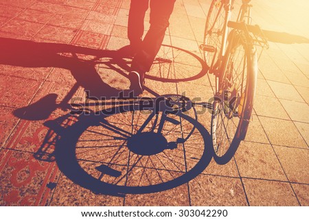 Shadow on Pavement, Man Pushing Bicycle on the Street, Urban Setting, Retro Toned Image