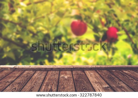 Apple orchard background, wood table for product placement, selective focus, retro toned image