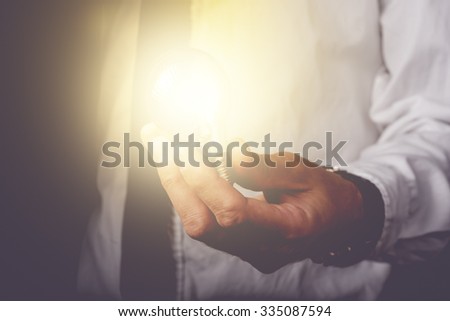 Business idea and vision, businessman holding light bulb, concept of new ideas, innovation, invention and creativity, retro toned image, selective focus.