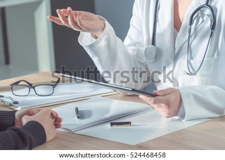 Female doctor advising patient in hospital office during regular medical exam, healthcare and prevention concept.