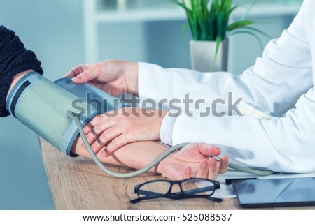 Doctor cardiologist measuring blood pressure of female patient in hospital office, health care control and monitoring.