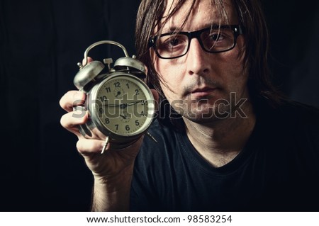 Adult man holding a vintage clock in low light interior