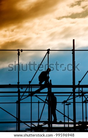 Construction site, silhouettes of workers on scaffolding against the light/