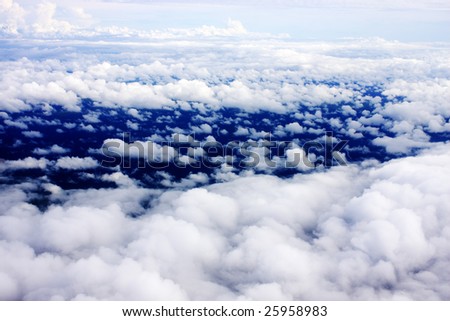 Aerial view of cloudy blue sky from aircraft window.