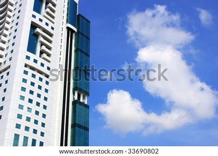 Partial view of modern building over cloudy blue sky.