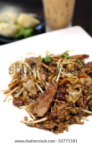 Close up of a dish of fried hor fun (rice noodle) on white plate.