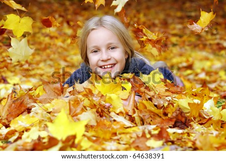 Girl in the park under falling autumn leaves