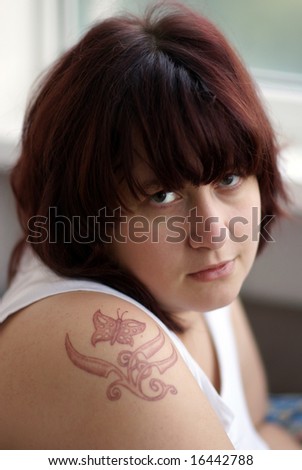 Face of young woman with tattoo on the shoulder