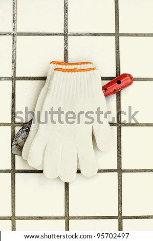 working gloves and scoop on white tile background
