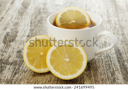 cup of hot lemon tea and lemons