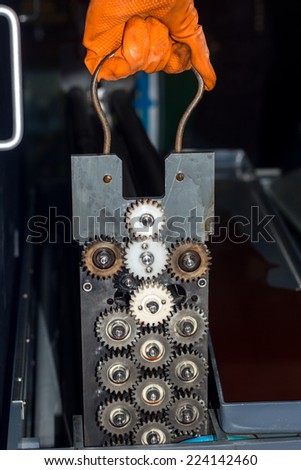 Gloved hands repairing gears of photo printer