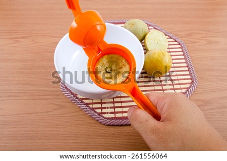 Lemon Squeezer with lemons and juice on wooden background.