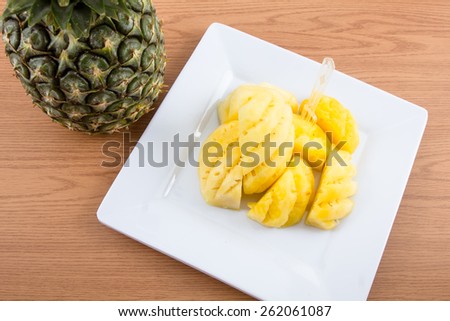 Pineapple on dish on wooden background.