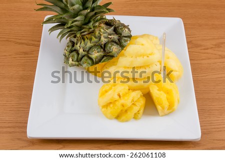 Pineapple on dish on wooden background.