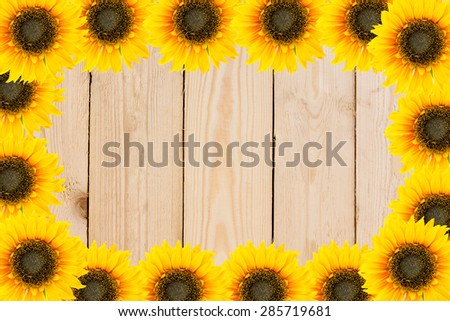 Frame of garden tools and flowers. Yellow sunflowers on wood background.