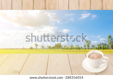 Coffee cup with wood texture on blur green rice field.
