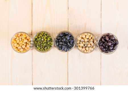 a lot of black bean, green beans, soybean, roasted coffee beans on wood texture background