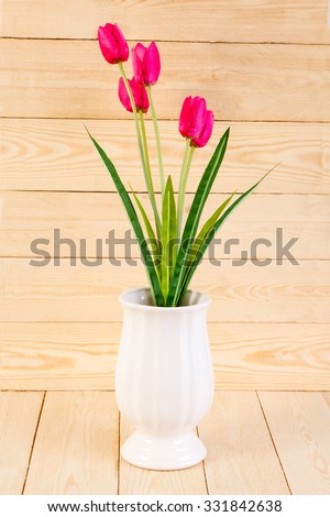 Red tulips in pot on wood texture background