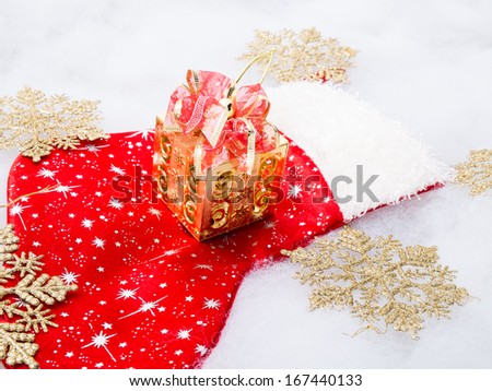 Golden gift box with bow on big red sock and golden snowflakes