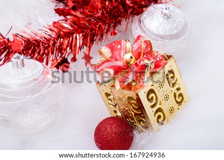 Golden gift box with bow and red theme decoration on snow