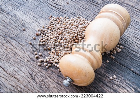 white peppercorns and wooden pepper shaker on wooden table top