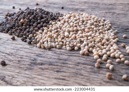 black and white peppercorns on wooden table top