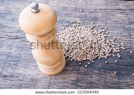 wooden pepper shaker and white peppercorns is background on wooden table top